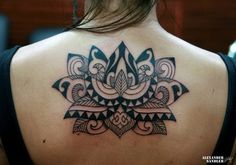 the back of a woman's neck with an intricate tattoo design on her shoulder