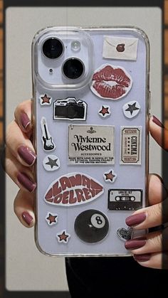 a person holding up a cell phone case with stickers on it and other items