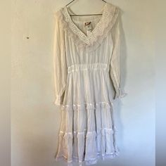 This Dress Is Og Cottagecore. She Is A Romantic Midi Dress With Lots Of Beautiful Lace Accents. She’s Light And Flowy With A V Neck And Lace Around The Neckline. The Skirt Is Triple Tiered! Gunne Sax Are Such Beautiful Dresses! Vguc For A Vintage Piece. A Few Small Spots Of Discoloration Which Are Pictured. Says Size 9 But Please Note That It Is A Vintage Size And Probably Much Smaller Than A Current Size 9. Please See My Measurements. Smoke Free, Cat Friendly Home Vintage Long Sleeve Midi Dress With Ruffles, White Midi-length Cottagecore Vintage Dress, White Midi Length Cottagecore Vintage Dress, White Cottagecore Vintage Midi Dress, Vintage Ruffled Midi Dress, Vintage Ruffle Midi Dress, Vintage Midi Dress With Ruffles, Retro Vintage Midi Dress With Ruffles, Vintage Midi Dress With Lace Trim For Spring