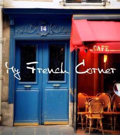 two tables and chairs in front of a blue building with red awnings on the door