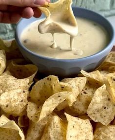 a person dipping tortilla chips into a bowl