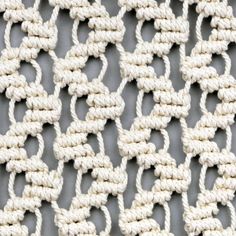 white crochet stitchs are arranged on a gray surface, forming an interlocked pattern