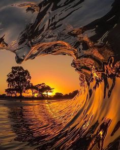 the sun is setting behind an ocean wave