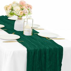 the table is set with white plates and green linens, along with gold chargers