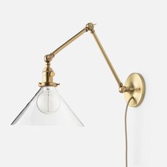 an antique brass wall light with clear glass shade on the arm and one bulb attached to it