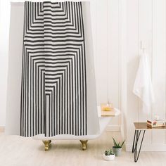 a bathroom with a black and white striped shower curtain next to a small potted plant