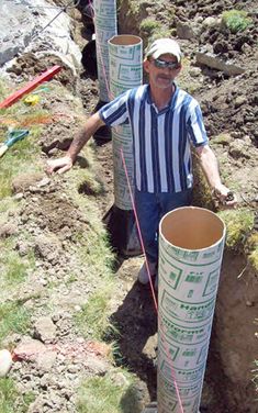 a man standing in the middle of a hole with two large tubes attached to it