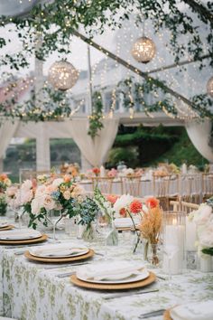 the tables are set with place settings and flowers in vases, candles, and plates