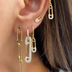 a close up of a person wearing gold earring with diamond links and chains attached to them