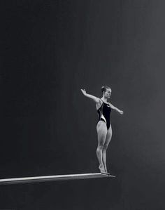 a black and white photo of a woman in a leotard on a balance beam