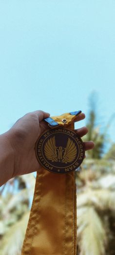 a person holding a medal in their left hand and palm trees in the back ground