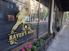 a store front with flowers in the window and a raven's manor sign on it