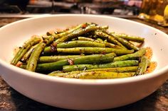 a white bowl filled with green beans on top of a counter