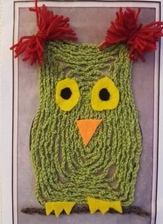 an owl made out of green yarn with red hair and eyes on it's head