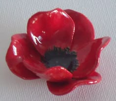 a red flower sitting on top of a white table