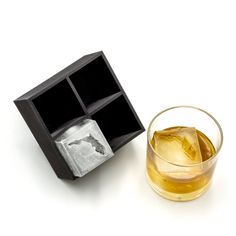 a glass with ice cubes in it next to a black box filled with ice