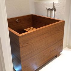 a wooden box sitting on top of a white floor next to a wall mounted faucet