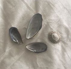 three seashells and a shell on a white sheet with a bead in the middle