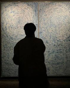 a man standing in front of a painting with circles on it's back wall