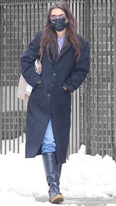 a woman walking in the snow wearing a face mask