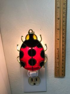 a red and black ladybug light sitting on top of a white wall