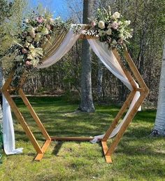 Exude luxury and opulence into your wedding ceremony by setting up a mesmerizing arch backdropOpt for a double sided hexagonal wooden arch stand and bedeck it with gold sequin and white chiffon fabric drapes to exude grandeurArrange a bunch of pinkwhite roseswhite hydrangeasbaby breaths and lush green foliage on the stand for a breathtaking display that’ll elevate your wedding ceremony decorations to the next level. Hexagon Arbor, Diy Wedding Arbor, Backyard Trellis, Diy Arbour, Diy Wedding Arch, Wedding Arbors, Wedding Arbor, Enchanting Wedding