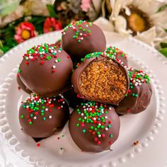 chocolate covered candies on a plate with sprinkles and flowers in the background