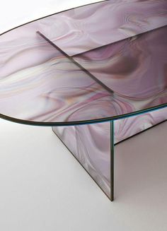 an oval glass table with purple swirls on the top and bottom, sitting on a white surface