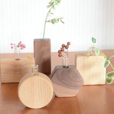 three wooden vases with flowers in them on a table next to two small containers