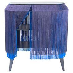 a blue cabinet with fringe curtains on it's sides and shelves in the middle