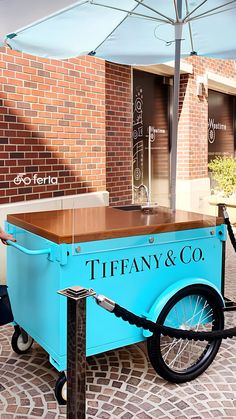 an ice cream cart with wheels and a wooden table in front of a brick building