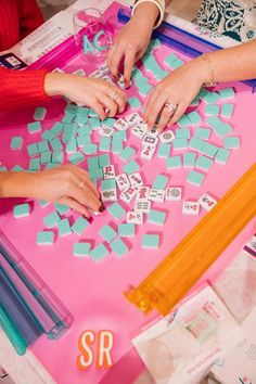 two women are playing with small tiles on a table