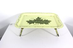 a green tray with leaves on it sitting on a white table next to a pair of scissors