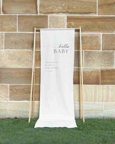 a white banner with the words hello baby on it next to two wooden clothes pins