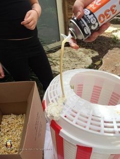 a woman is pouring something into a trash can