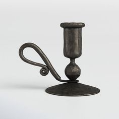 an old fashioned candle holder on a metal stand with a hook and looped handle