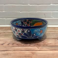 a blue bowl sitting on top of a wooden table next to a white brick wall