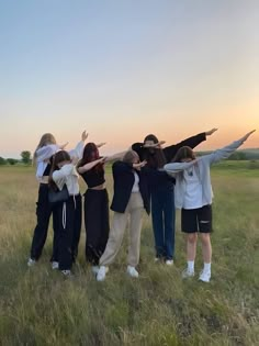 a group of people standing on top of a grass covered field with their arms in the air