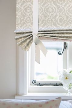 a white flower sitting on top of a window sill next to a vase with flowers in it