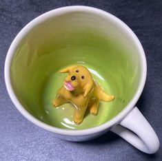 a yellow dog figurine in a green cup