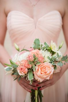 a woman holding a bouquet of flowers in her hands and wearing a wedding ring on her finger