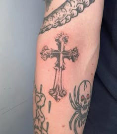 a person with a cross tattoo on their arm and some skulls around them, all in different colors