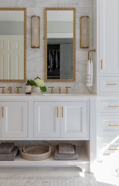 a white and gold bathroom with two mirrors