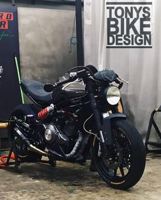 a black motorcycle is parked in front of a sign that says tony's bike design