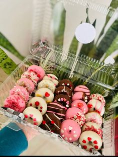 a plastic container filled with lots of different types of donuts on top of a table