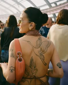 a woman with tattoos on her back standing in front of other people