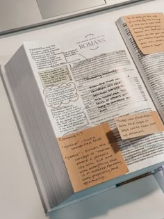 an open book with sticky notes attached to it sitting on top of a computer keyboard