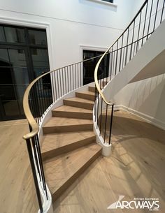 there is a spiral staircase in the middle of an empty room with white walls and wood floors