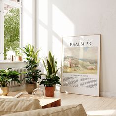 some plants are sitting on a table in front of a large framed poster that says psalm 23