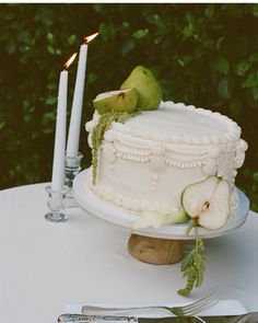 a white cake sitting on top of a table next to a knife and two candles